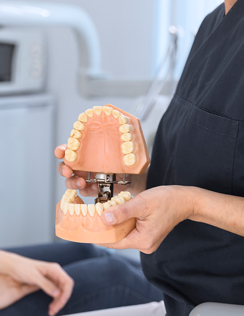 https://hd-smile.com/wp-content/uploads/2024/09/close-up-dentist-showing-teeth-model-smiling-patient.png