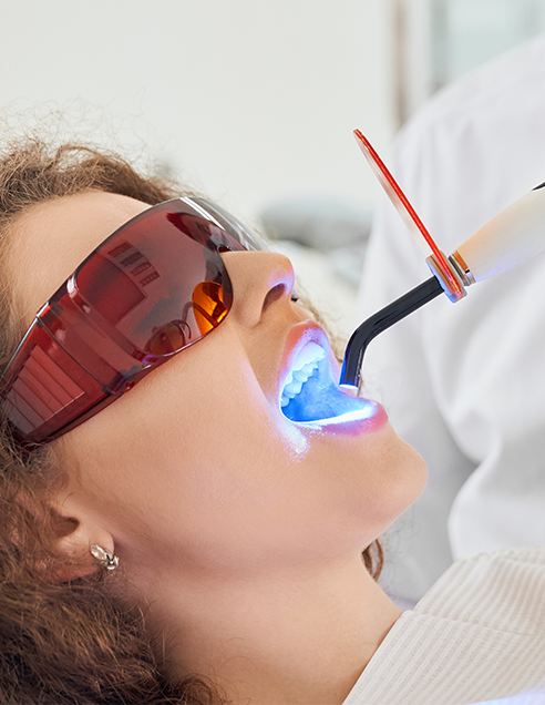 https://hd-smile.com/wp-content/uploads/2024/09/girl-lying-chair-while-dentist-keeping-ultraviolet-tool.png